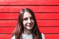 portrait of young smiling woman against red wooden wall background