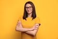 Beautiful mixed race girl in eyeglasses smiling on yellow background