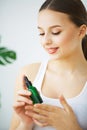 Portrait of a young smiling woman holding a green bottle with co