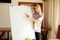 Portrait of young smiling woman lecturer speaker businesswoman standing at whiteboard, presenting business in office. Royalty Free Stock Photo