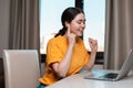Portrait of a young smiling woman sitting at a desk wearing headphones chatting online on a laptop. The concept of online courses Royalty Free Stock Photo