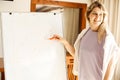 Portrait of young smiling woman speaker businesswoman standing at whiteboard drawing graph with orange marker in office. Royalty Free Stock Photo