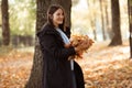 Portrait of young smiling woman standing walking, holding huge pile of yellow fallen leaves in forest park, having fun. Royalty Free Stock Photo