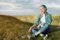 Portrait of young smiling woman traveler with multi-colored hair. Sitting high in the mountains in the evening with a Royalty Free Stock Photo