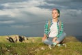 Portrait of young smiling woman traveler with multi-colored hair. Sitting high in the mountains in the evening with a Royalty Free Stock Photo