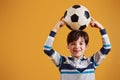 Portrait of young soccer player with ball. Stands against yellow background Royalty Free Stock Photo