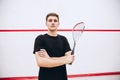 Cropped portrait of young sportive man, professional squash player posing isolated over sport studio background Royalty Free Stock Photo