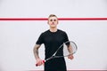 Cropped portrait of young sportive man, professional squash player posing  over sport studio background Royalty Free Stock Photo