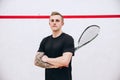 Cropped portrait of young sportive man, professional squash player posing  over sport studio background Royalty Free Stock Photo