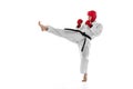 Portrait of young sportive man wearing white dobok, helmet and gloves practicing isolated over white background. Concept