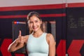 Portrait of Young sports woman smiling and looking at camera, Happy girl showing thumbs up in fitness gym Royalty Free Stock Photo