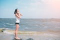 Portrait of young sporty woman in headphones relaxing while sitting near ocean in summer , attractive female listening Royalty Free Stock Photo