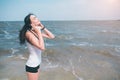 Portrait of young sporty woman in headphones relaxing while sitting near ocean in summer , attractive female listening Royalty Free Stock Photo