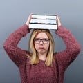 Portrait of a young student woman holding books on head against gray background.Tired of learning/studying concept