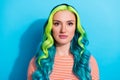 Portrait of young stunning peaceful female with long wavy green vibrant hairstyle isolated on blue color background