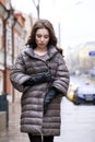 Portrait of a Young stylish brunette girl in a gray down jacket