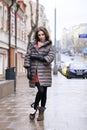 Portrait of a Young stylish brunette girl in a gray down jacket