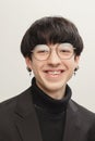 Portrait of young stylish man with piercing, in glasses posing, cheerfully smiling  over grey studio background Royalty Free Stock Photo