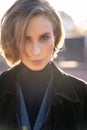 Young blond short-haired woman in velvet coat, vest and sweater on sunny street Royalty Free Stock Photo