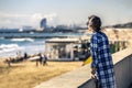 Portrait of young and stylish woman standing on the sea-front next to the sandy beach.