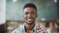 Portrait of young successful African businessman at busy office. Handsome male looking at camera and start smiling. Royalty Free Stock Photo