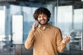 Portrait of young successful businessman, hispanic man smiling and looking at camera, man inside office building talking Royalty Free Stock Photo