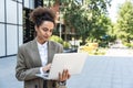 Portrait of young successful businesswoman office worker using laptop computer outside office building in formal wear. Royalty Free Stock Photo