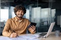 Portrait of young successful financier accountant at work inside office building at workplace, hispanic man smiling and Royalty Free Stock Photo