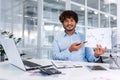 Portrait of young successful financier paperwork inside office, man smiling and looking at camera shows graph with Royalty Free Stock Photo