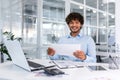 Portrait of young successful hispanic businessman inside office, man smiling and looking at camera, paper worker happy