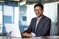 Portrait of young successful hispanic businessman inside office, man smiling and looking at camera sitting at desk using Royalty Free Stock Photo