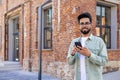 Portrait of young successful student outside university campus, man smiling looking at camera and using app on phone Royalty Free Stock Photo
