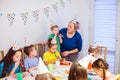 Supportive mother helping little boy to blow party horn