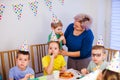 Supportive mother helping little boy to blow party horn