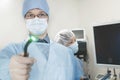 Portrait of young surgeon holding a medical instrument towards the camera, light shining