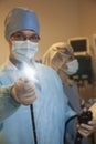 Portrait of young surgeon holding a medical instrument towards the camera, light shining