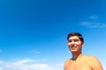 Portrait of a young tanned smiling guy on the beach against a blue cloudless sky