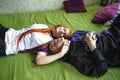 Portrait of a young tattooed punk couple of a girl and a guy with long dyed hair braided, lying on a large bed. Hugging Royalty Free Stock Photo