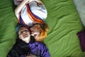 Portrait of a young tattooed punk couple of a girl and a guy with long dyed hair braided, lying on a large bed. View Royalty Free Stock Photo