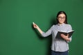 Portrait of young teacher with book and chalk on green background Royalty Free Stock Photo