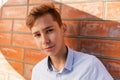 Portrait of a young teenage boy in a shirt, against a red brick wall Royalty Free Stock Photo