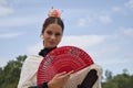 Portrait of young teenage girl in black dance dress, white shawl and pink carnations in her hair, dancing flamenco with a red fan Royalty Free Stock Photo