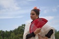 Portrait of young teenage girl in black dance dress, white shawl and pink carnations in her hair, dancing flamenco with a red fan Royalty Free Stock Photo