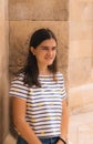 Portrait of a young teenage girl with long hair smiling in a striped t-shirt with yellow suns against the background of a stone Royalty Free Stock Photo