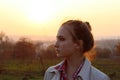 Portrait of a young teenage girl looking to the side over sunset sky background. Young girl outdoor.