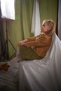 Portrait of a young teenage girl sitting on chair among a green and white fabric background in a photo studio. A little Royalty Free Stock Photo