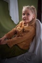 Portrait of a young teenage girl sitting on chair among a green and white fabric background in a photo studio. A little Royalty Free Stock Photo