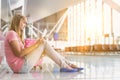 Portrait of young teenage girl sitting on the floor and using digital tablet while waiting for her flight in airport Royalty Free Stock Photo