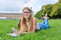 Young student girl lying on grass, educational building background