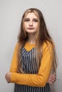 Portrait of young teenage girl in yellow shirt and classic black and white stripe apron on light grey background. Calm face Royalty Free Stock Photo